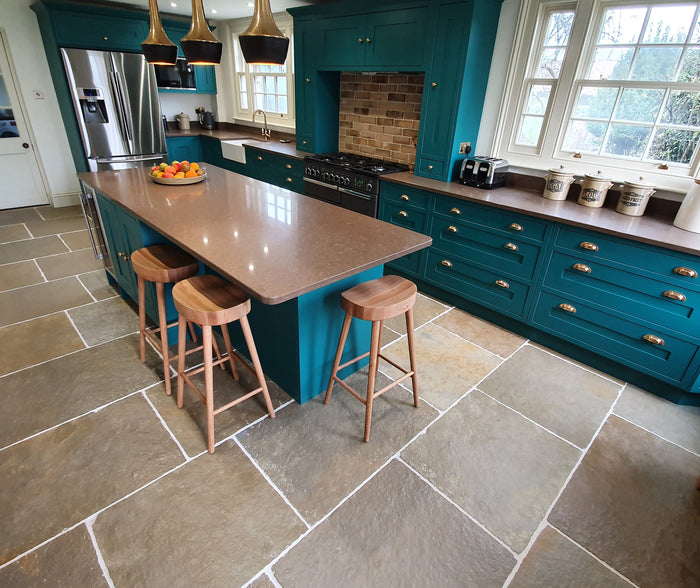 Natural Stone Online Minster Antiqued Limestone Tiles in rustic farmhouse country home kitchen with blue kitchen cabinets and kitchen island